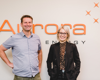 A man and a woman standing in front of an Aurora Energy sign.
