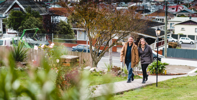 Photo of a man and woman, hand in hand walking up a garden path toward the camera. The house is behind the camera.