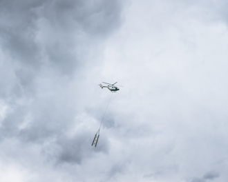 Helicopter flying with part of a tower being towed underneath it