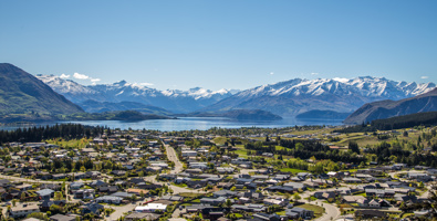 Wanaka township looking toward the lake on a sunny day with snow-capped mountains in the background