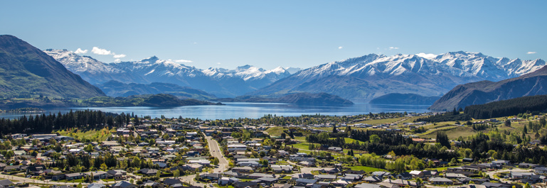Wanaka township looking toward the lake on a sunny day with snow-capped mountains in the background