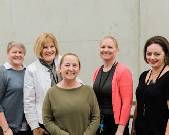 A group of women standing together smiling to camera.