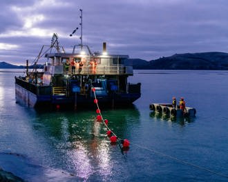 Ferry heading across the harbour in low light laying submarine electricity cable