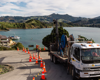 Truck on a hairpin corner winding a power cable into a large reel above the Marine Science Centre at Portobello