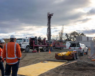 Photo shows two workers in foreground of the Omakau substation construction site