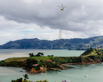 Helicopter removing part of an electricity tower, flying away with it towed underneath