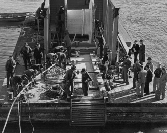 1947, the original submarine electricity cable being lowered into the Otago Harbour from a boat