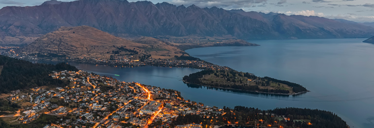 Photo of Queenstown lit up at dusk.
