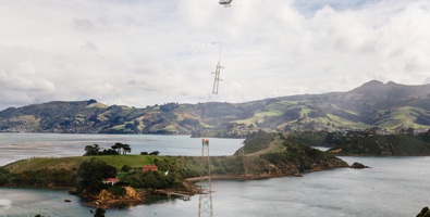 Helicopter lifting tower at Portobello with Otago Harbour in the background.